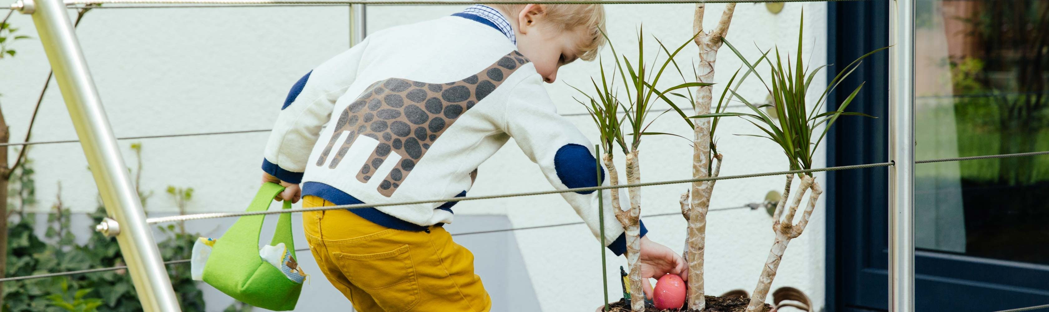 Osternest – Kleiner Junge findet farbiges Ei in Blumentopf