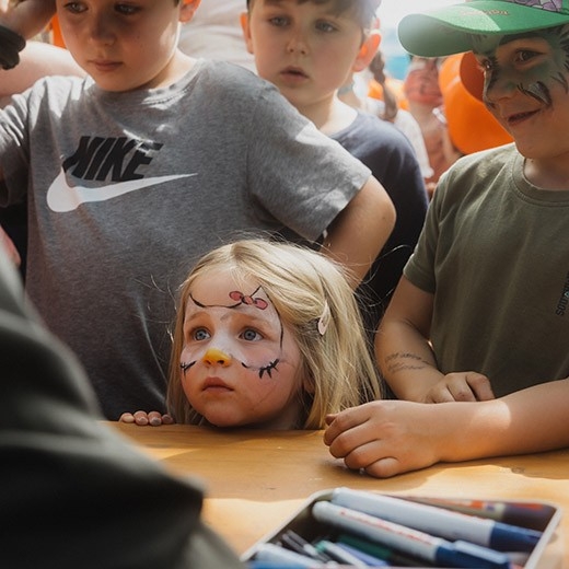Kinderland Openair – Ein Kind mit geschminktem Gesicht sitzt an einem Tisch – eine lebendige Festivalatmosphäre.