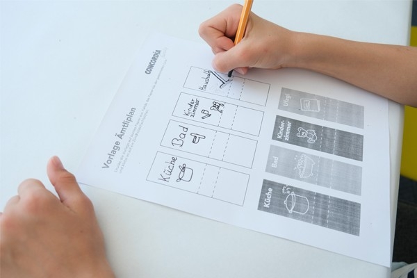 Ämtliplan: Kind schreibt Ämtli auf Vorlage