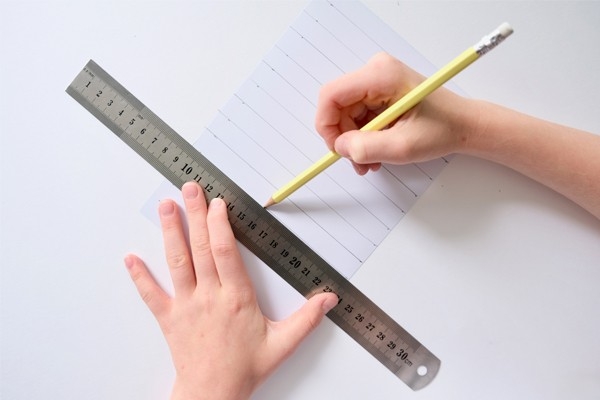 Christbaumkugeln – Kind misst Papier mit Lineal ab