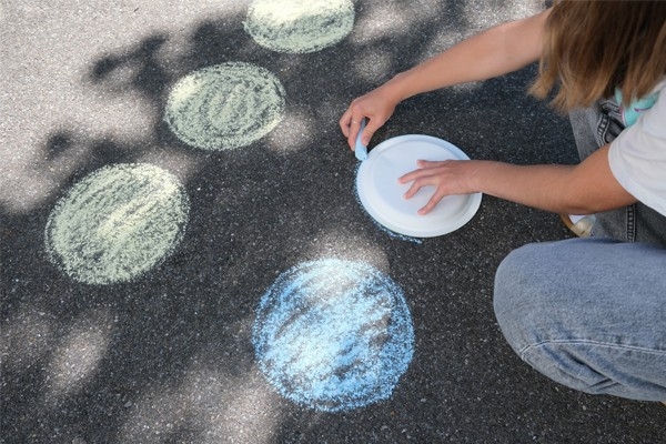 Twister – Kind malt mit Kreide Kreise auf Strasse