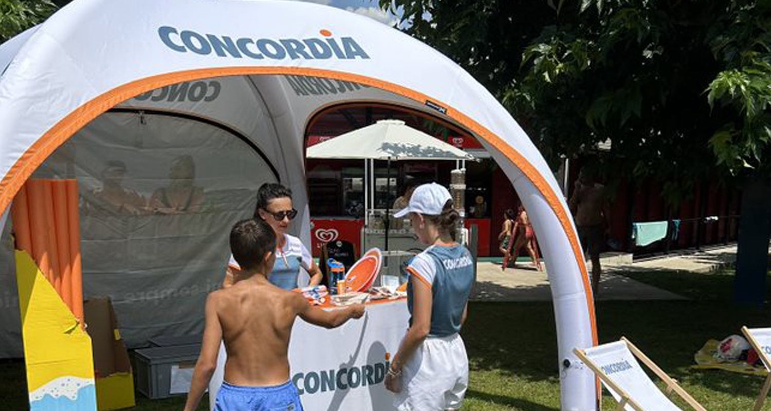 Badi-Tour 2025 - Ein Junge steht in Badehosen am CONCORDIA-Stand.