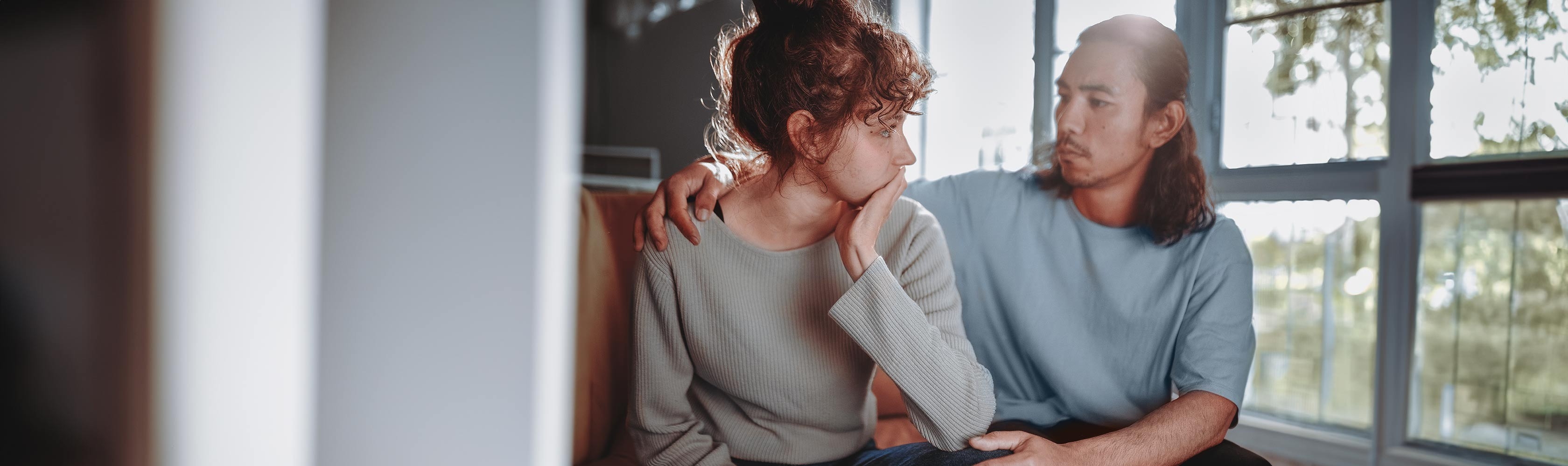 Babyblues – Eltern sitzen vor dem Fenster und umarmen sich