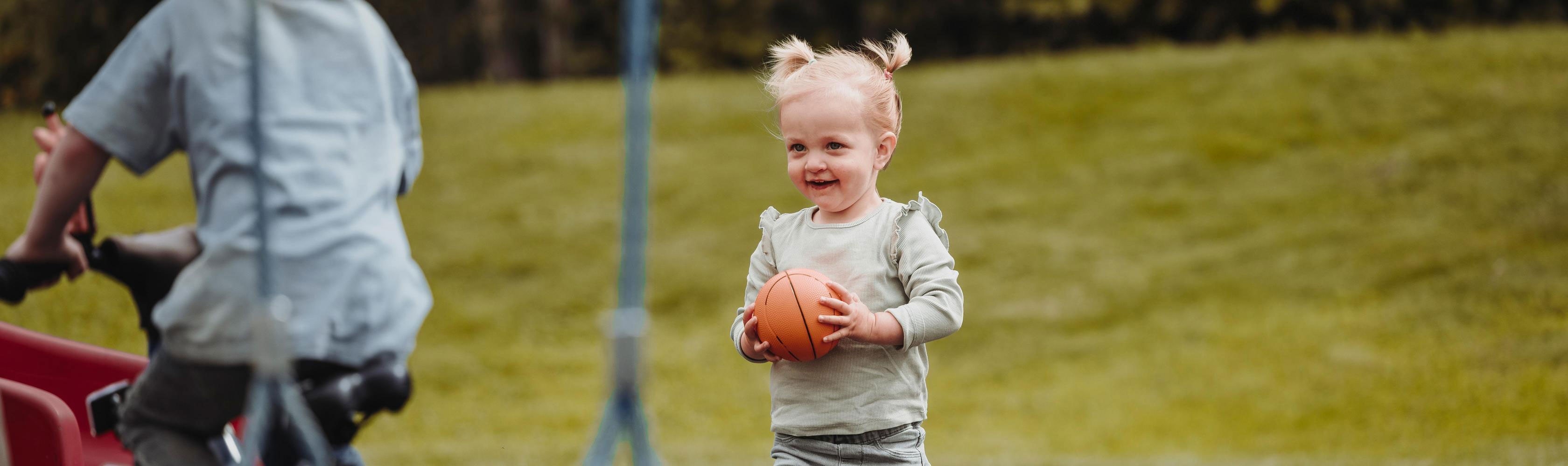 Zeckenbiss - Kleines Mädchen steht im Grass mit einem Ball