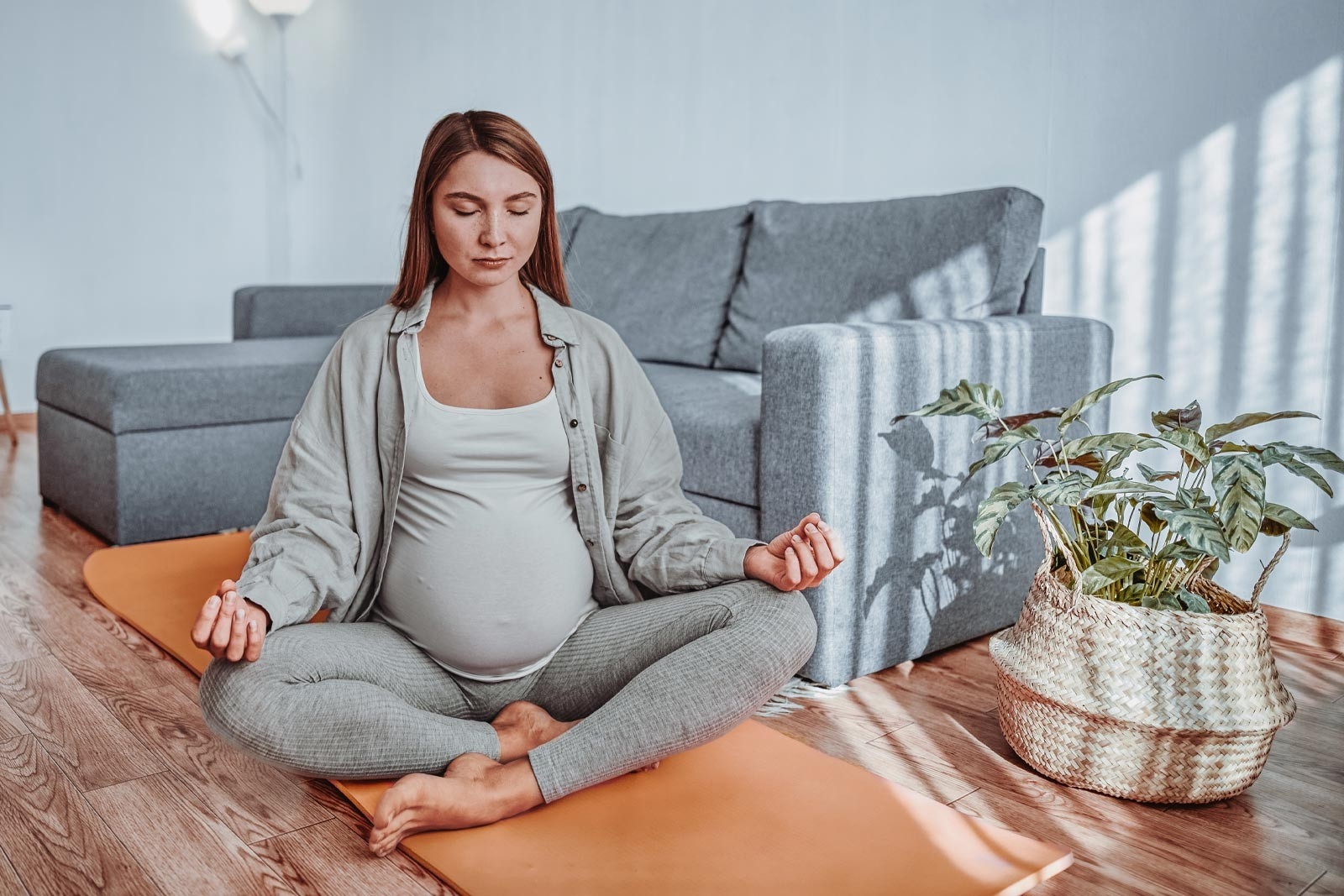 Rückenschmerzen Schwangerschaft – Schwangere Frau sitzt am Boden und macht Yoga