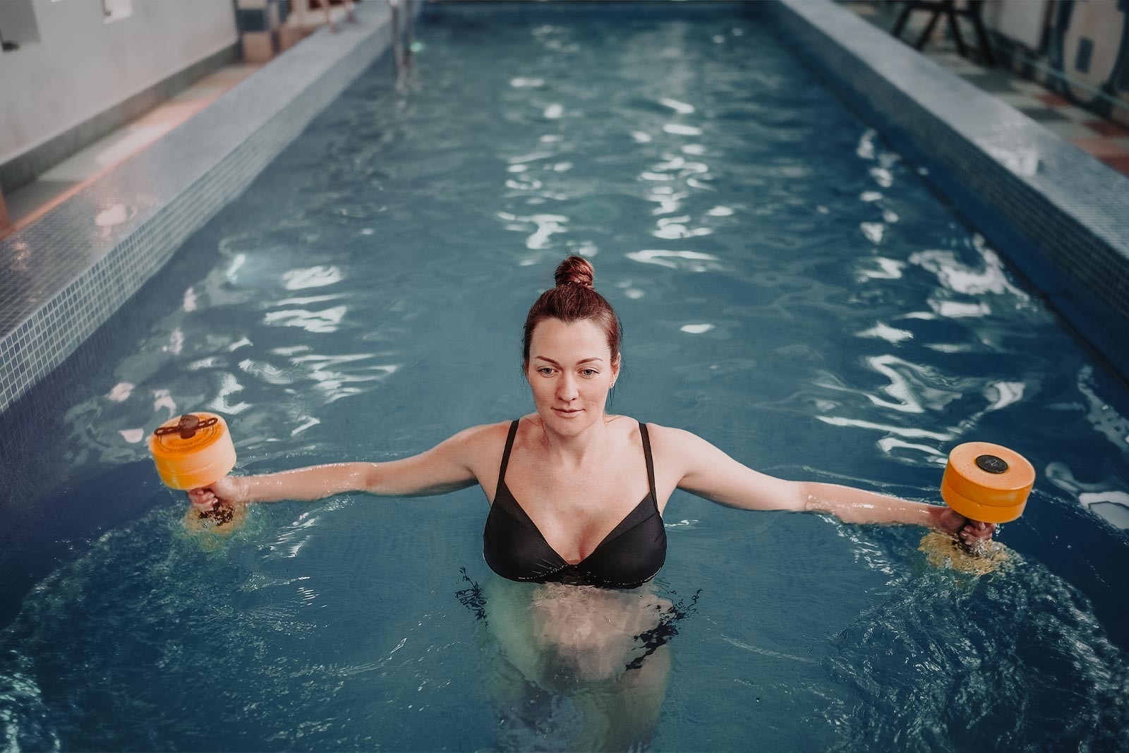 Rückenschmerzen Schwangerschaft – Schwangere Frau ist im Schwimmbecken und macht Übungen