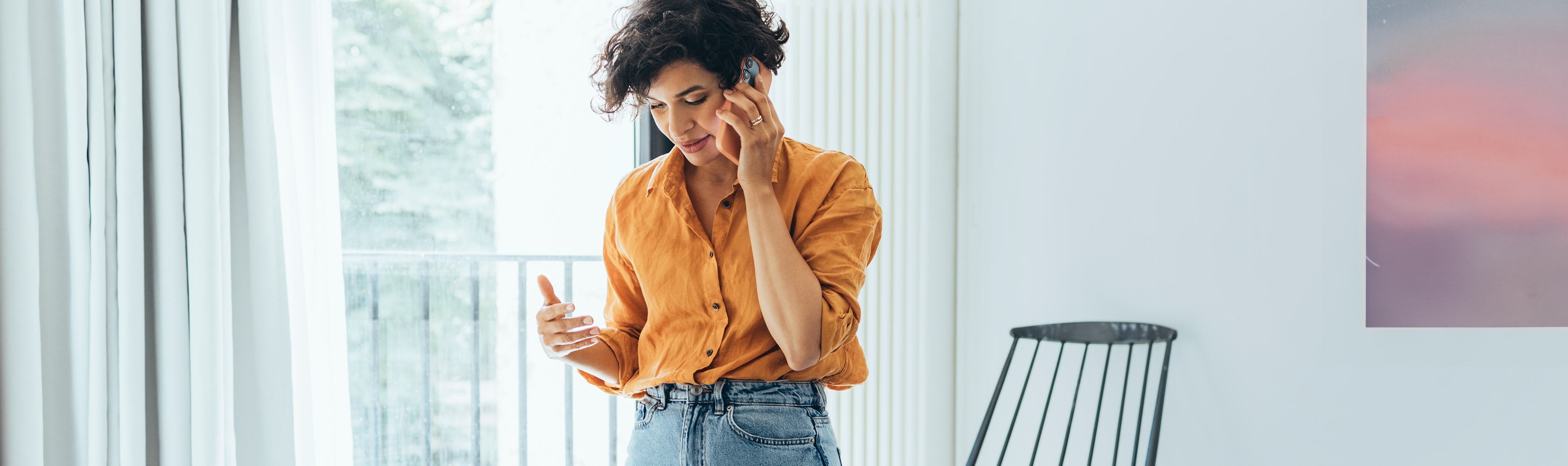 Eine Hand hält ein oranges Telefon vor einer Anthrazit farbigen Wand um einen Anruf an die CONCORDIA zu Kennzeichnen