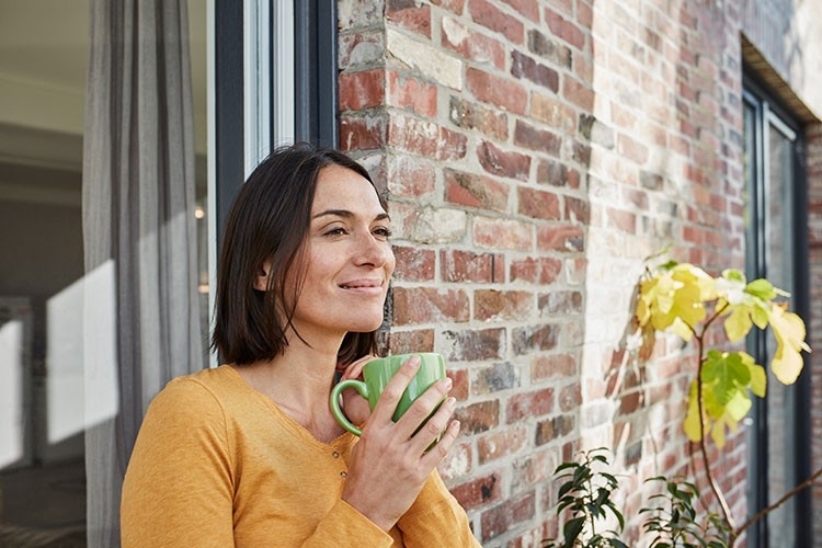 Eine junge Frau geniesst im Freien eine feine Tasse Tee mit Heilkräutern
