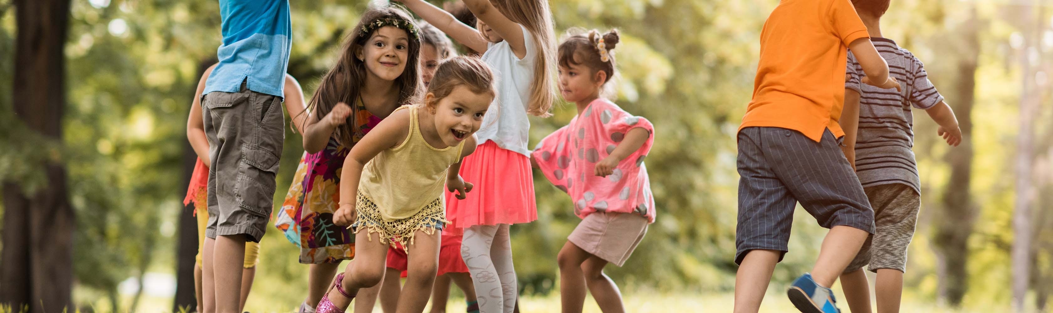 Kinder spielen auf Wiese miteinander und lachen