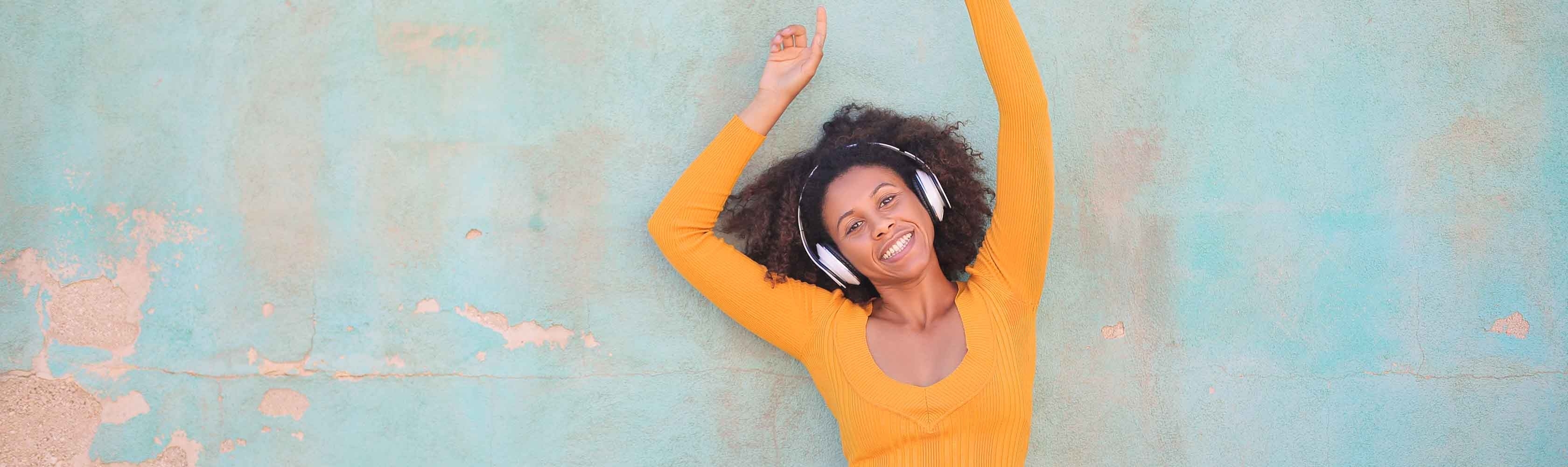 Tanzende Frau mit Kopfhörern vor blauem Hintergrund