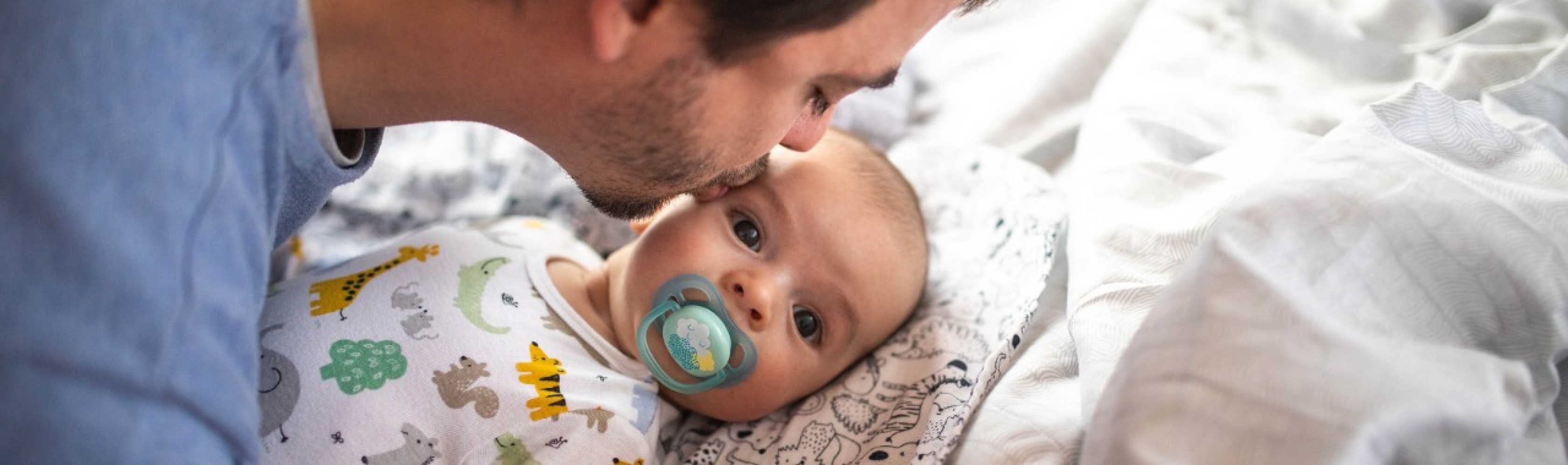 Vater küsst Baby auf der Stirn.