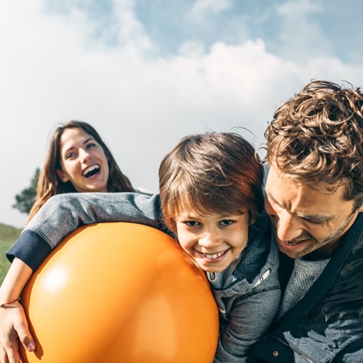 Knabe mit Vater. Im Hintergrund steht die Mutter