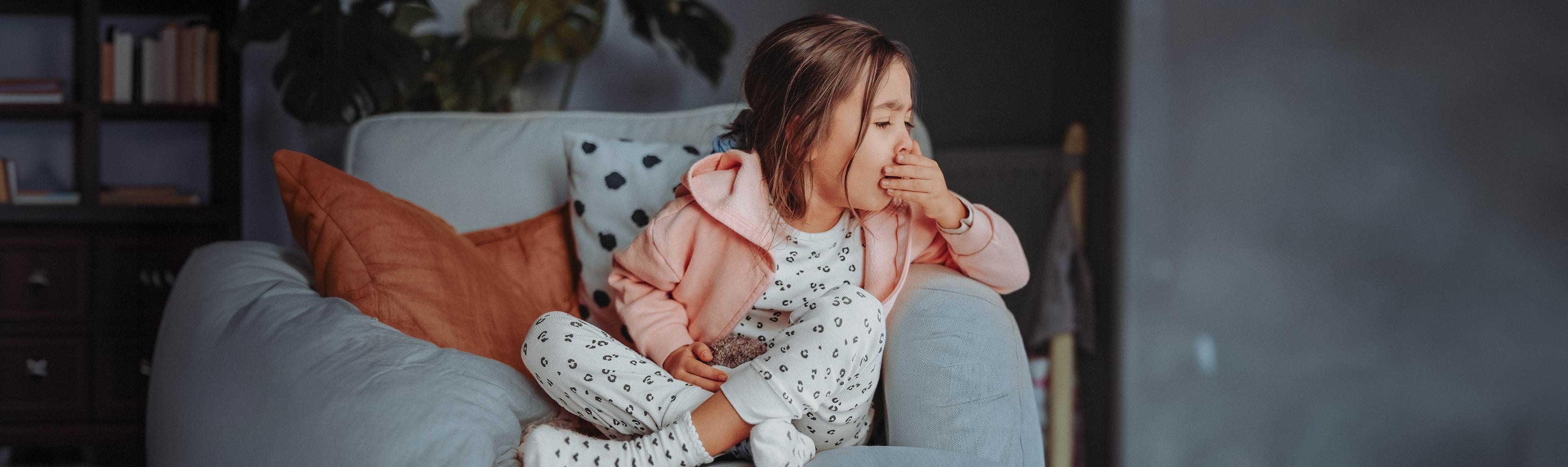 Pseudokrupp - Kleinkind sitzt auf einem Sessel und hustet in die Hand