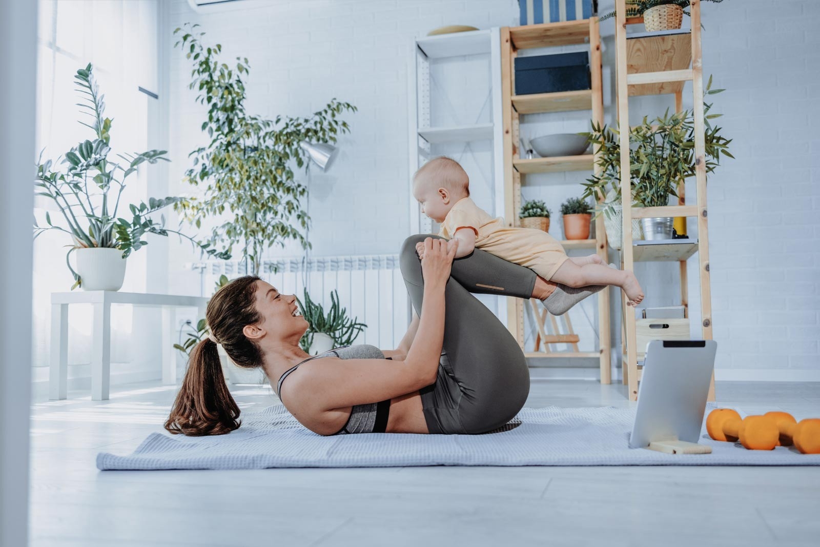 Postpartum exercise – a woman is doing her postpartum exercises for her abdomen with her baby