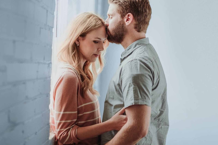 Unfulfilled wish to have children – a man is kissing a woman on the forehead, both have sad facial expressions