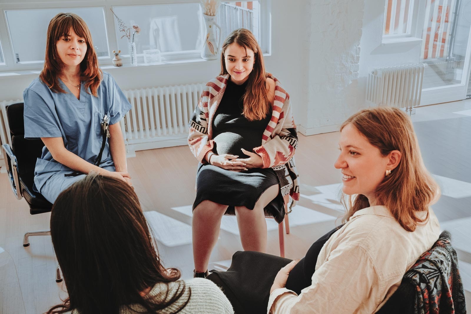 Health insurance and maternity – three pregnant women sit in a circle with a midwife and talk about preparing for the birth