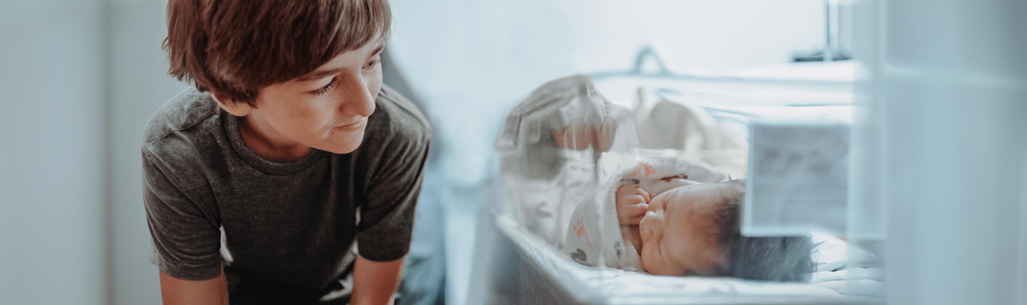 Pre-term birth – a boy looks at a newborn in an incubator