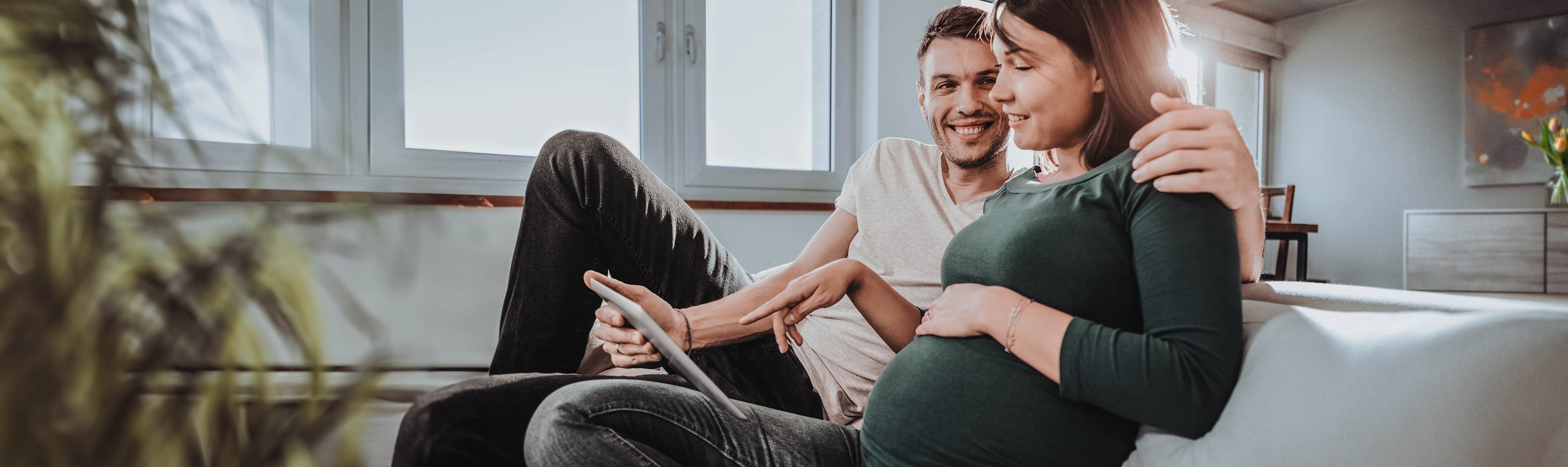 Birth options – a couple sits on the sofa looking at various birth options on a tablet.