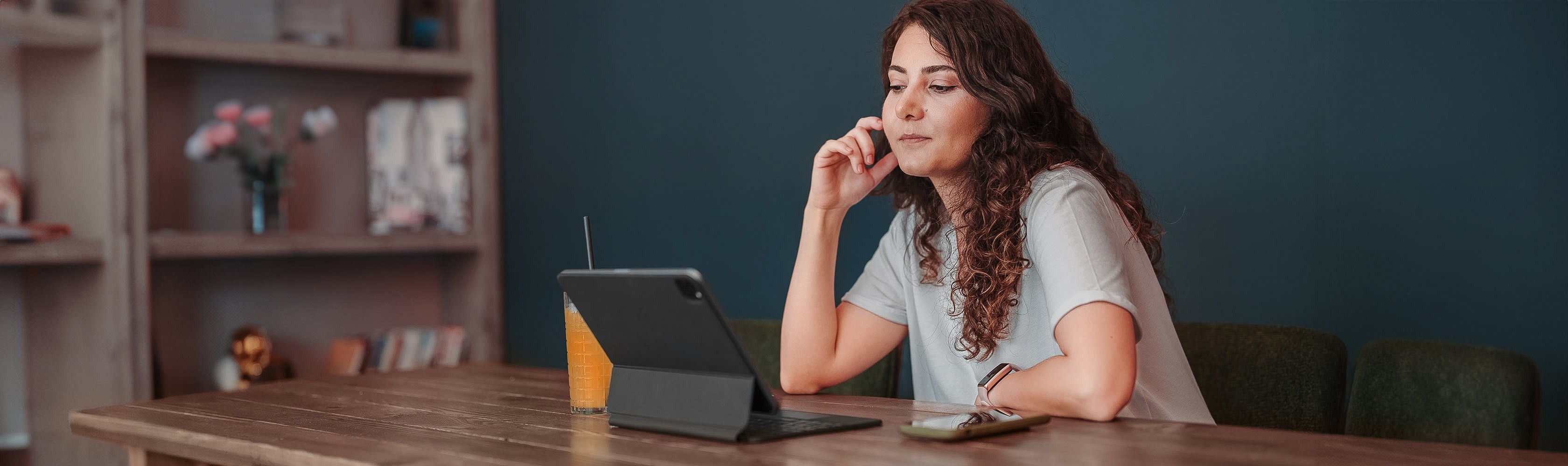 Ylah – Frau sitzt nachdenklich vor dem Tablet