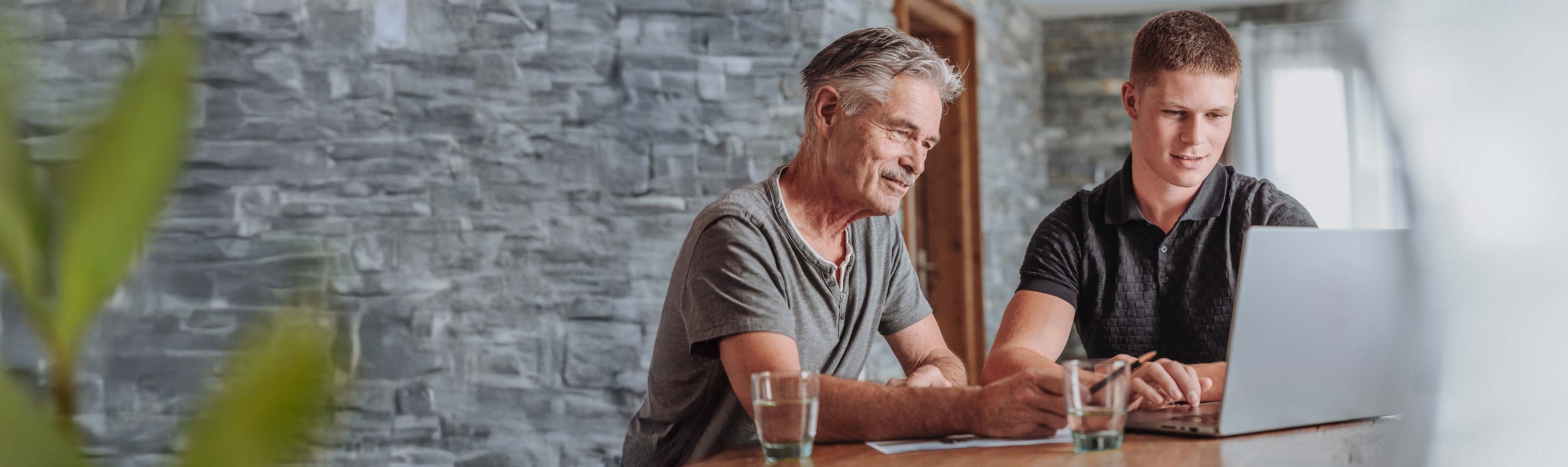Customer satisfaction – Senior and young man working together on laptop.