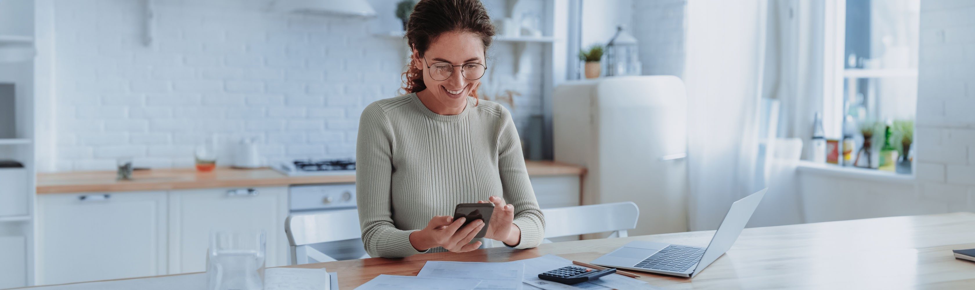 E-Bill - Une femme est assise à une table et paie ses factures avec eBill.