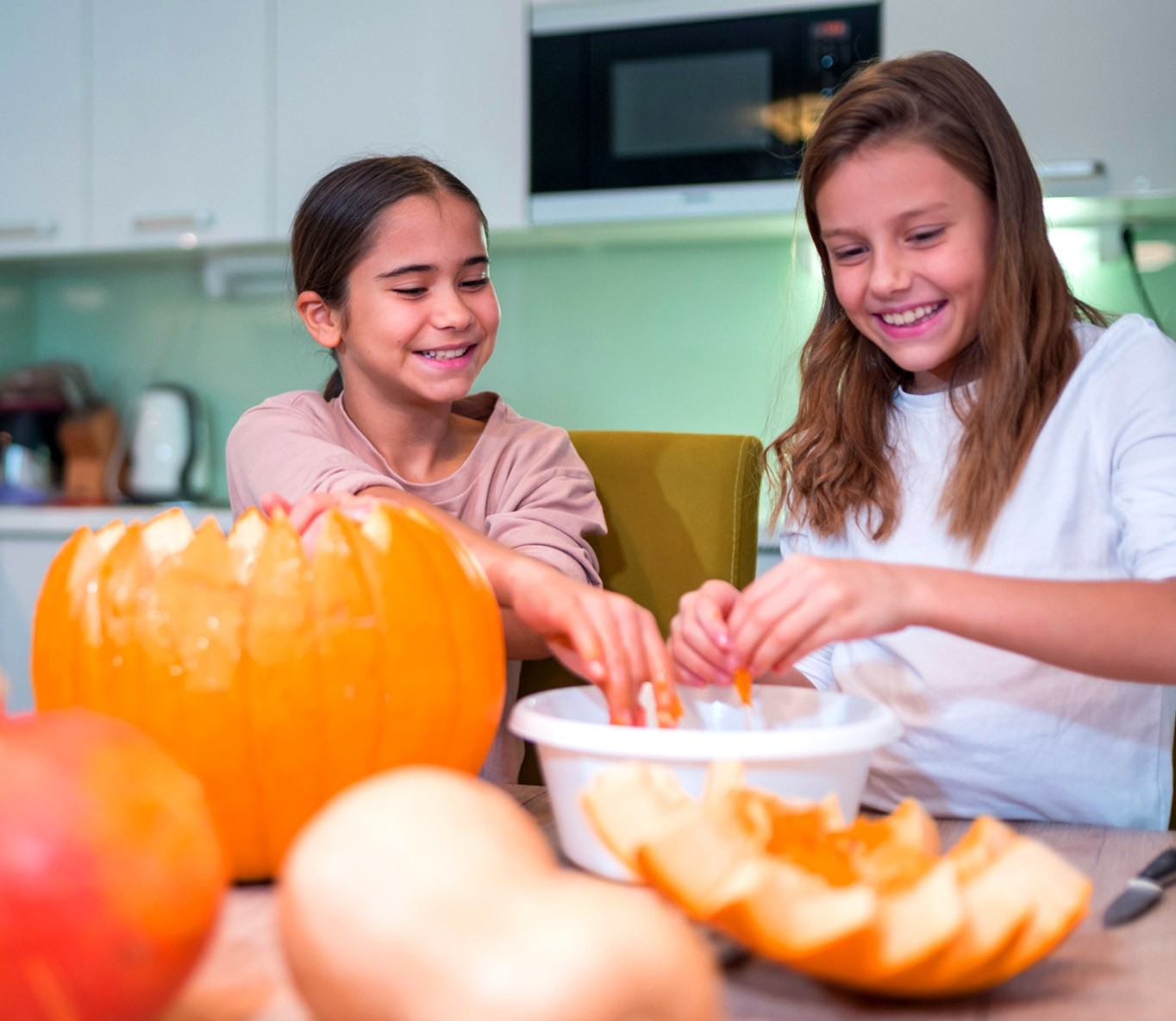 Kürbis Basteltechniken - zwei Mädchen schnitzen einen Kürbis