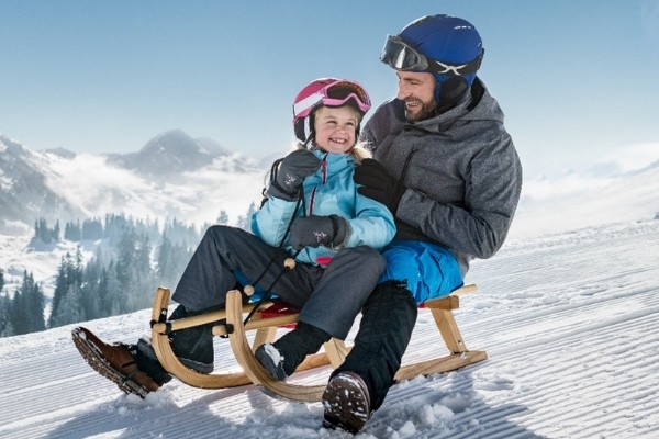 Un père est assis avec sa fille sur une luge