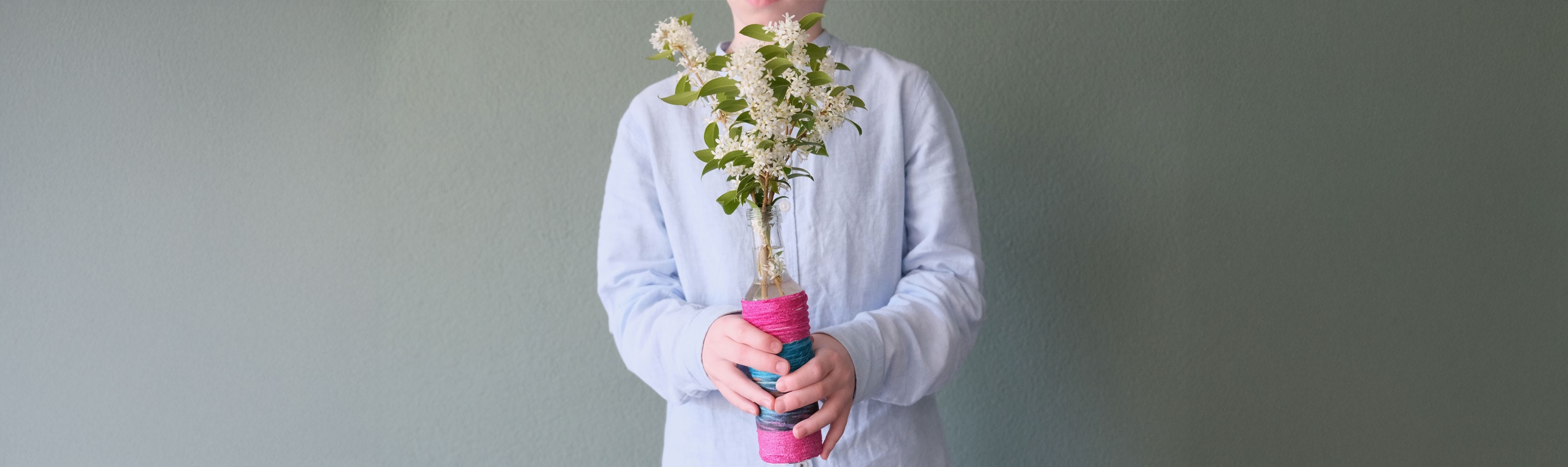 Schnurvase - Junge hält selbstgebastelte Schnurvase mit Blume drin in der Hand
