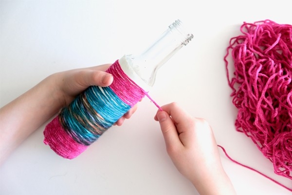 Vase à ficelle - l'enfant enroule une nouvelle ficelle colorée autour de la bouteille