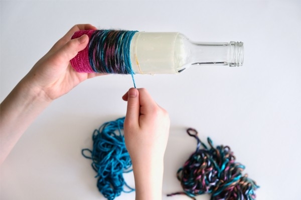 Vase en ficelle - l'enfant enroule une ficelle colorée autour de la bouteille