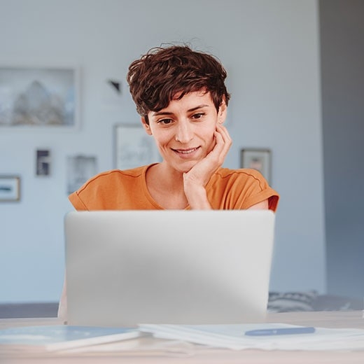 Prämien rechnen – Frau sitz am Laptop und macht sich Notizen auf Papier