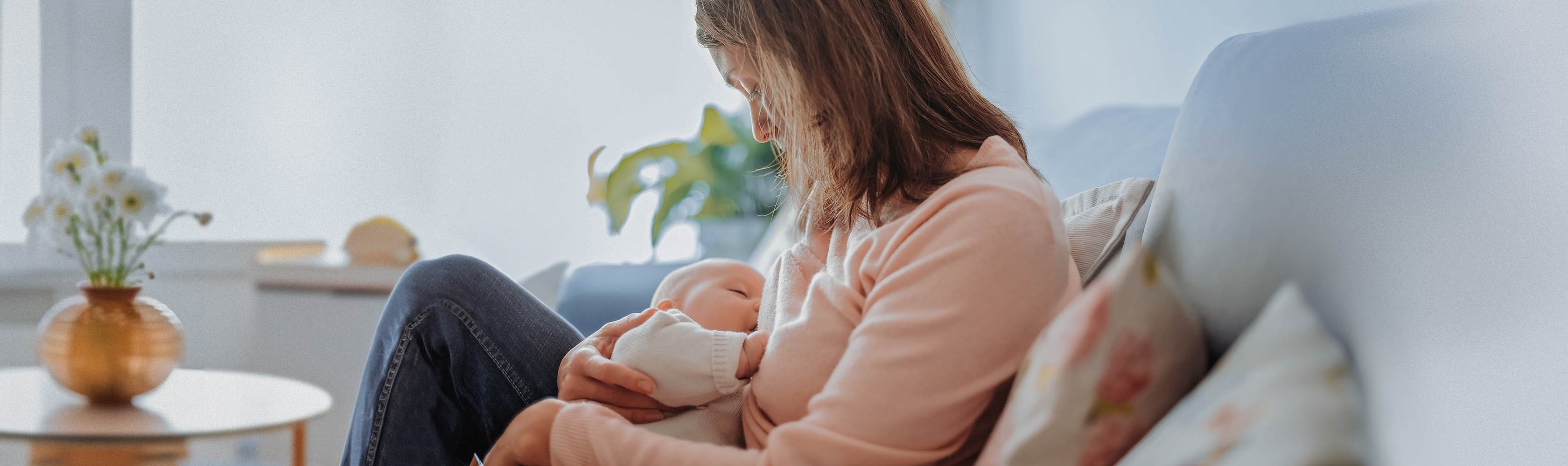 Allaitement - une femme allaite son bébé sur le canapé.