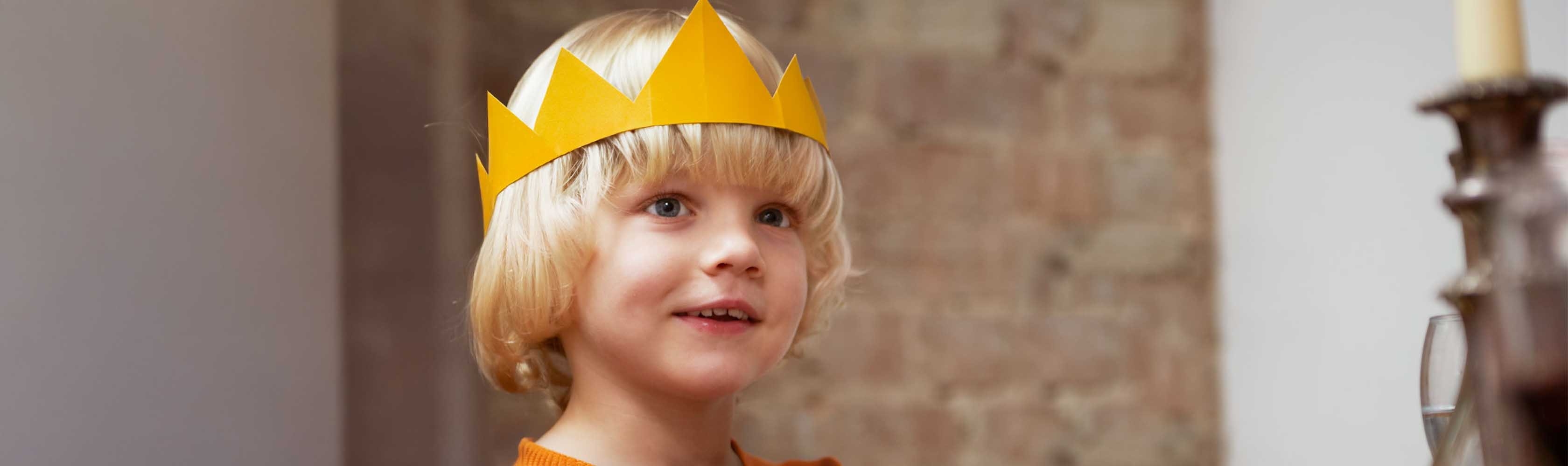 Un garçon coiffé d'une couronne dorée sourit.