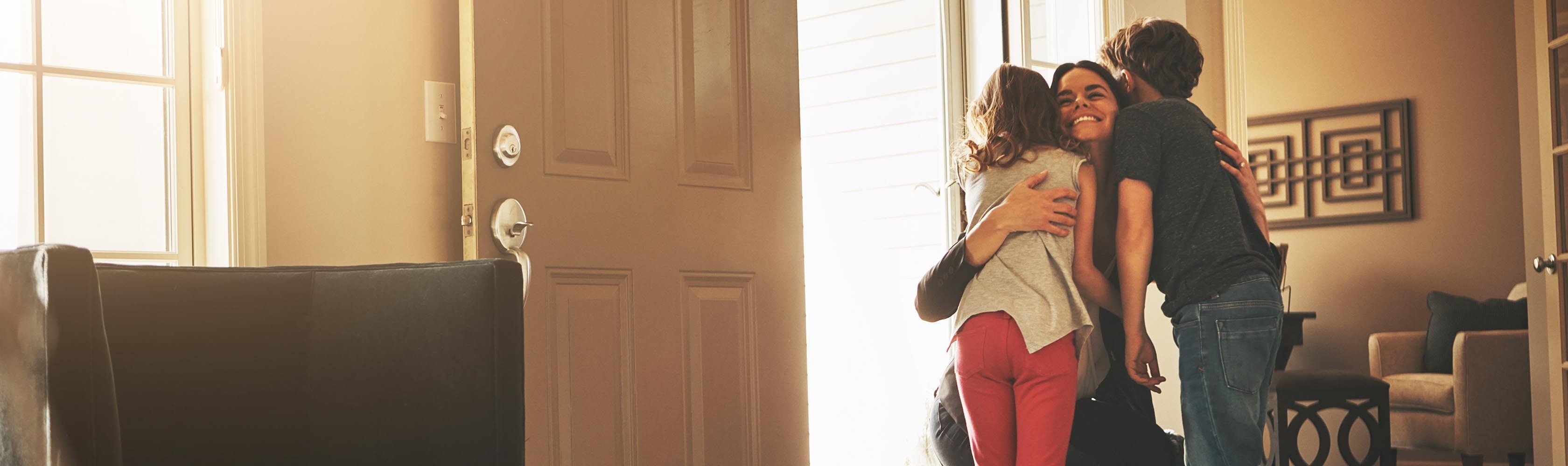 Une mère accueille chaleureusement ses deux enfants à la maison.