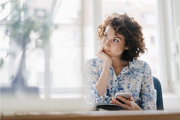 Une femme est assise à table, perdue dans ses pensées