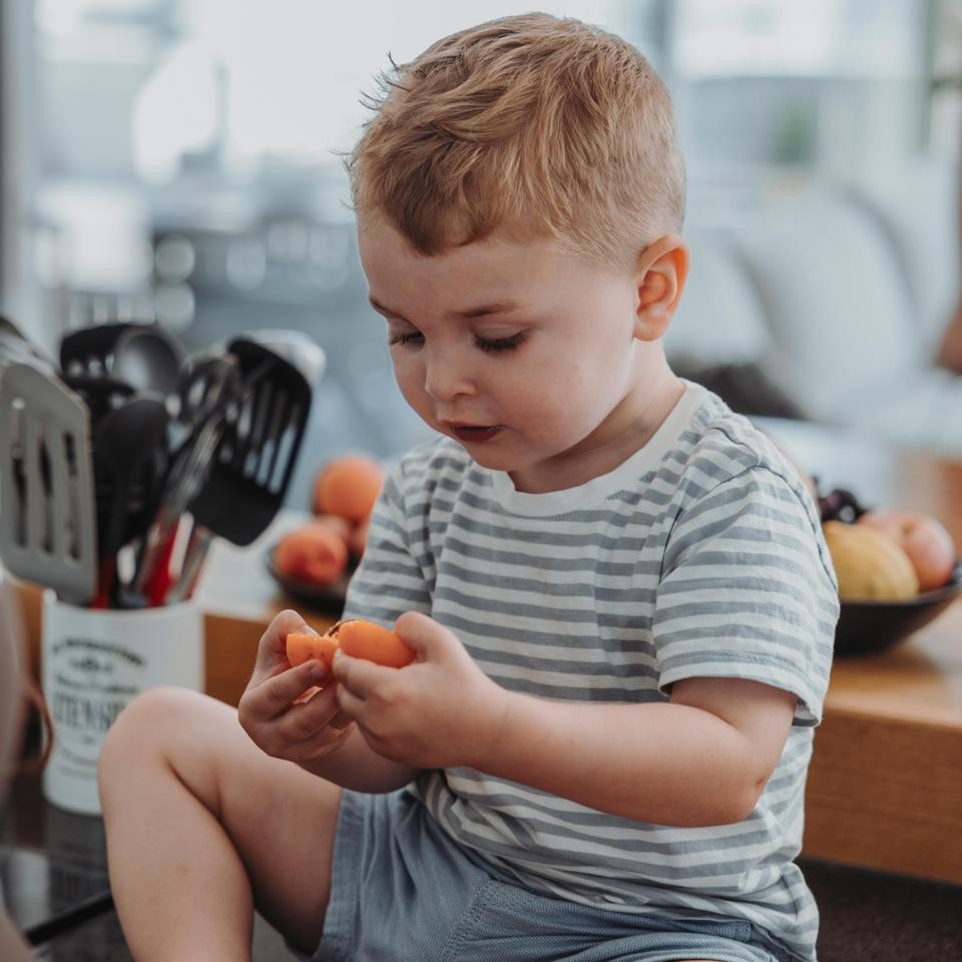 Un petit garçon goûte des abricots pour la première fois dans la cuisine