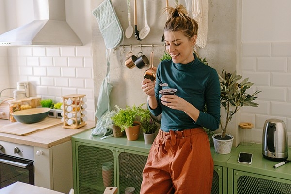 Une jeune femme prend une collation dans sa cuisine