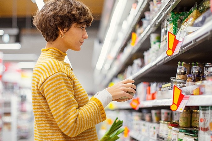 Une femme se tient devant un grand rayon dans un supermarché.