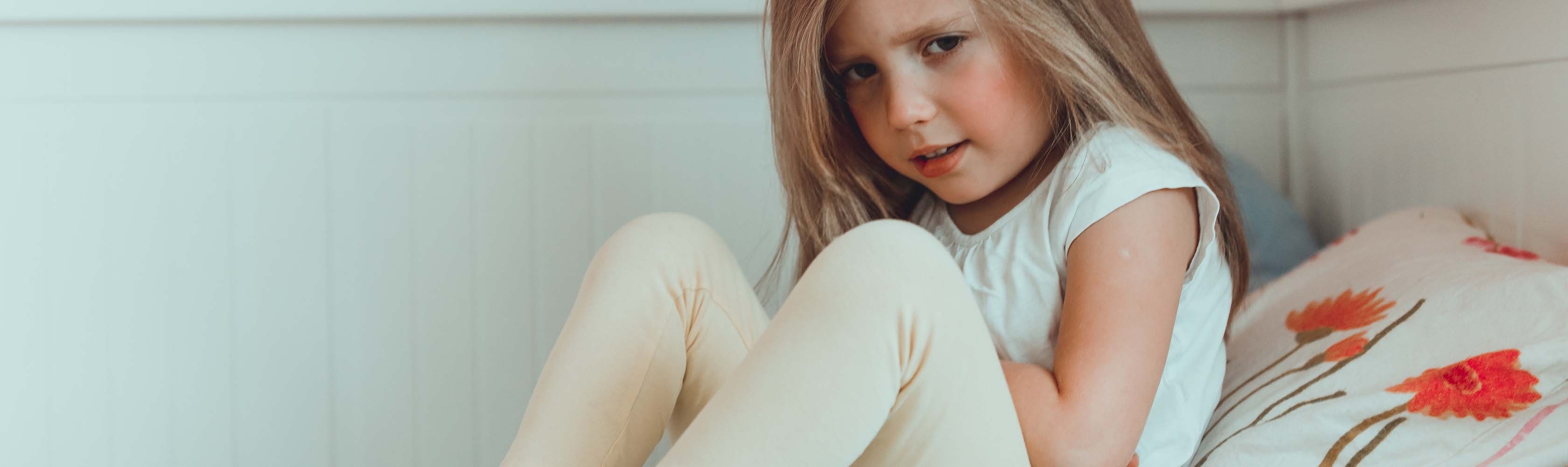 Tout-petit assis dans son lit avec des douleurs à l'estomac.