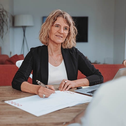 Informations annuelles 2025 - Une employée de CONCORDIA est assise à une table en bois et prend des notes lors d'un entretien de conseil