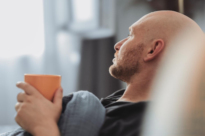 Schreibaby - Mann liegt auf dem Sofa und hält eine Teetasse in den Händen