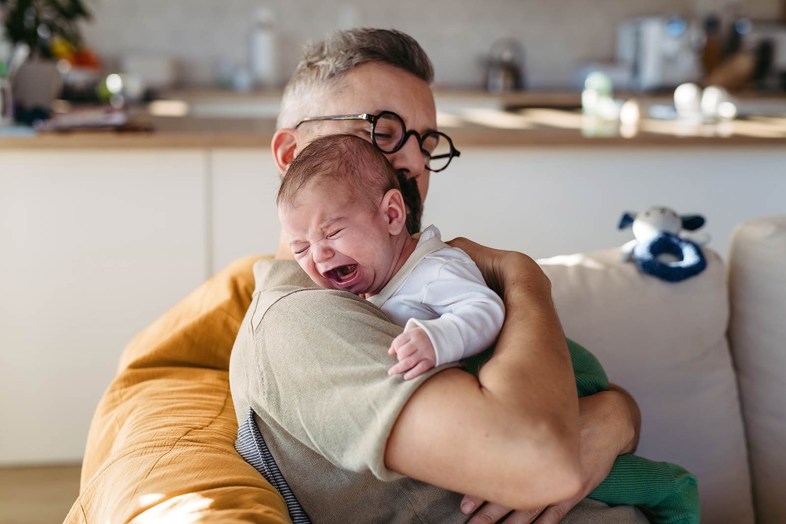Pianto inconsolabile: un padre tiene in braccio il bebè e cerca di calmarlo