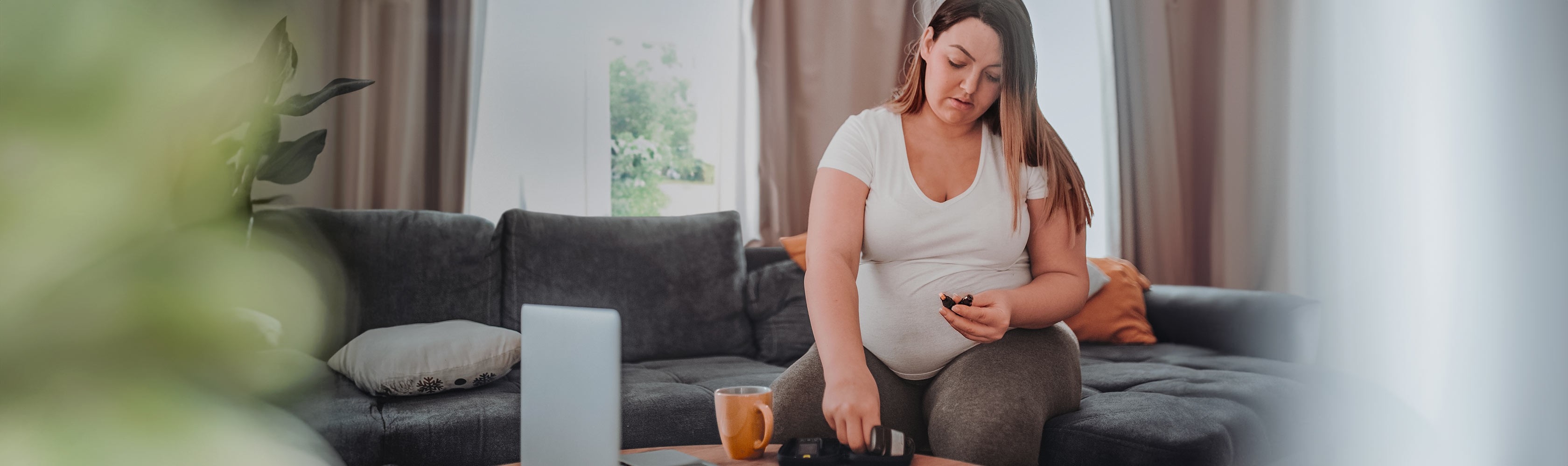Diabete in gravidanza: una donna in gravidanza è seduta sul divano e prepara il glucometro per misurare la sua glicemia.