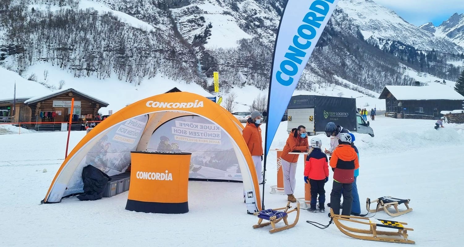 Schlittler:innen stehen vor dem Promo-Stand in Elm