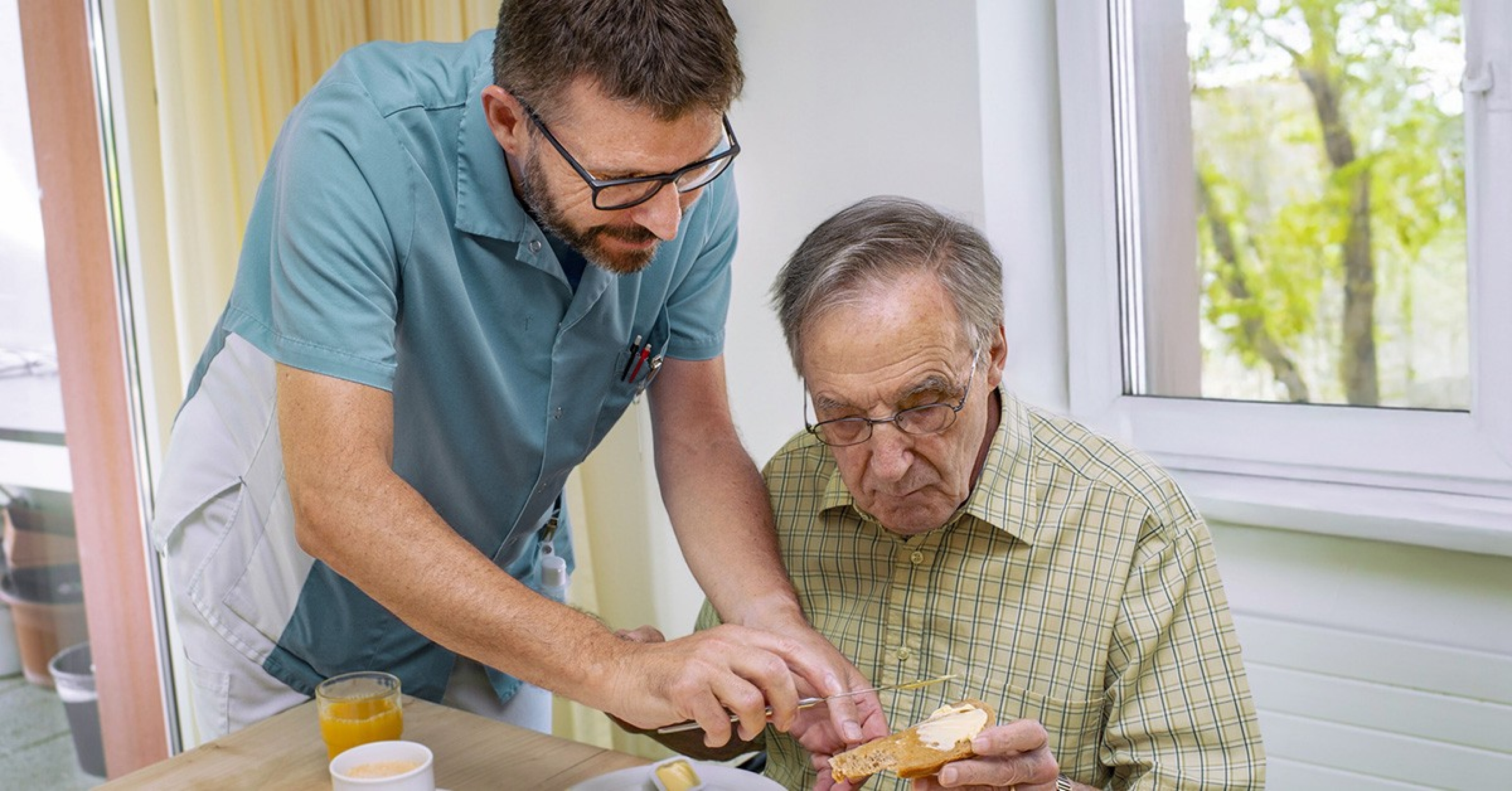 Matthias Renggli, assistente specializzato presso il centro di cura e assistenza per anziani Kirchfeld, aiuta un ospite del gruppo di residenza per persone affette da demenza a fare colazione.  