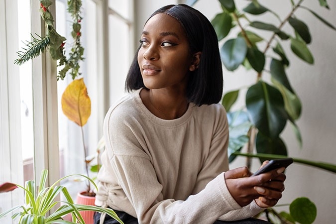 Una donna guarda fuori dalla finestra, persa nei suoi pensieri.