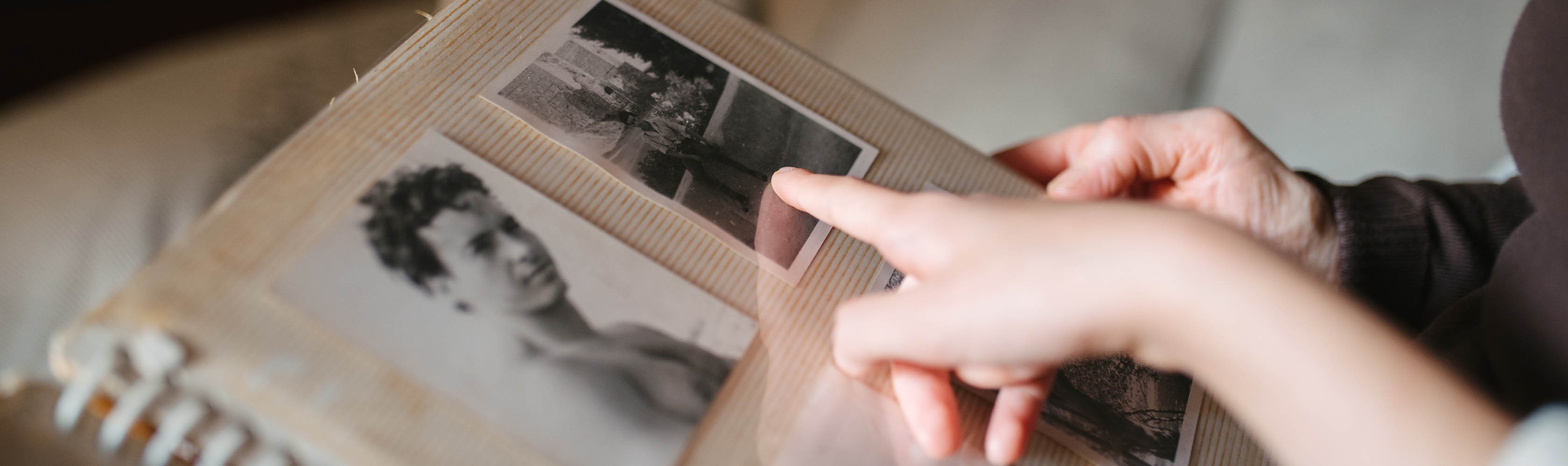 Una persona anziana sfoglia un vecchio album di foto insieme a un familiare e cerca di ricordare quei tempi.