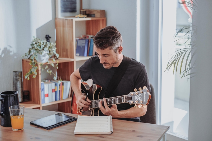 Assicurazione per me – uomo suona la chitarra e scrive musica a casa