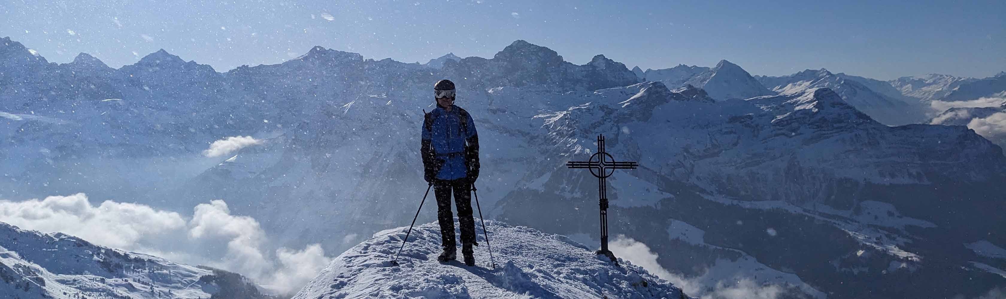 Ein Mitarbeiter der CONCORDIA und Mitglied des CONCORDIA Alpinclubs steht auf einem verschneiten Gipfel nach einer Skitour.