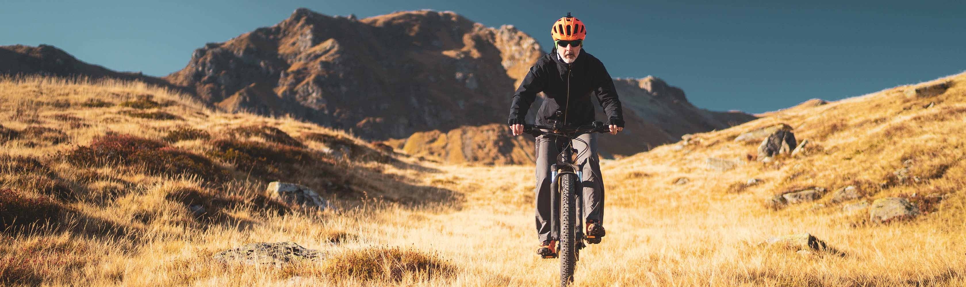 Ein Mann ist fit und sicher auf ihrem E-Bike in den Bergen unterwegs